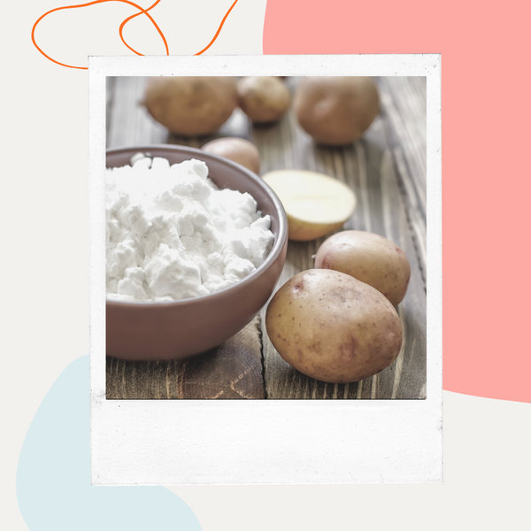 Potatoes and a bowl of potato starch on a wooden table