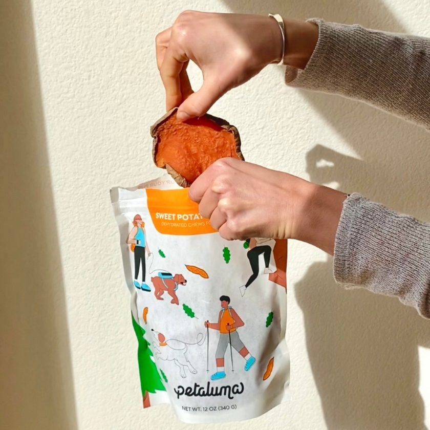 Load image into Gallery viewer, Picture of Sweet Potato Jerky being removed from the bag. Photo credit: The Quality Edit
