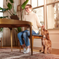 A woman working from home and feeding a dog a piece of Sweet Potato Jerky